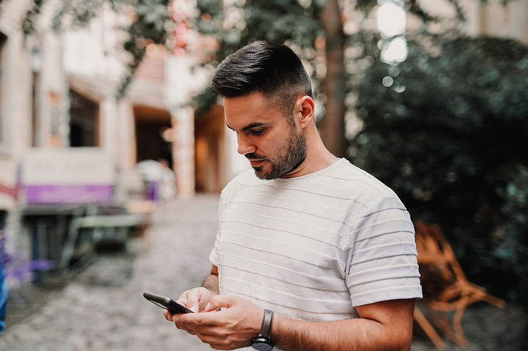 man looking down at mobile phone in his hand