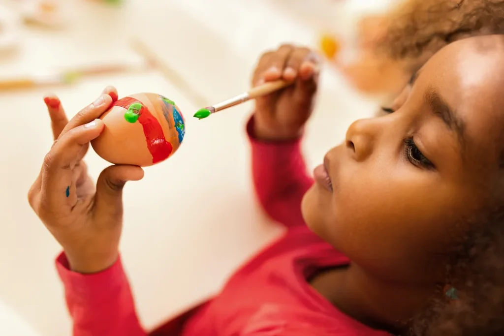 young girl painting an egg for easter