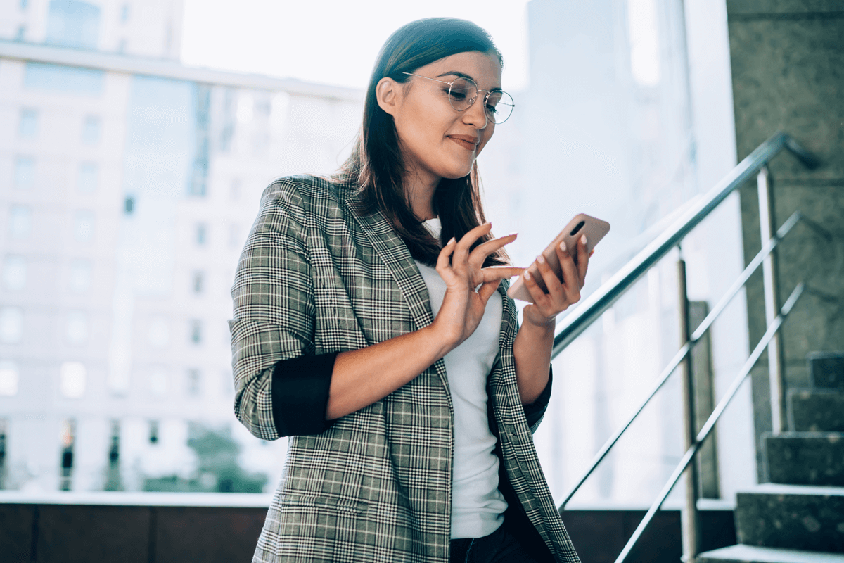 woman wearing glasses and looking at her phone for short term online loan with fasta