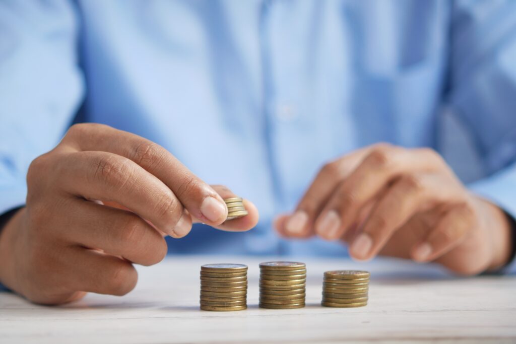 close up of man stacking 3 piles of small coins