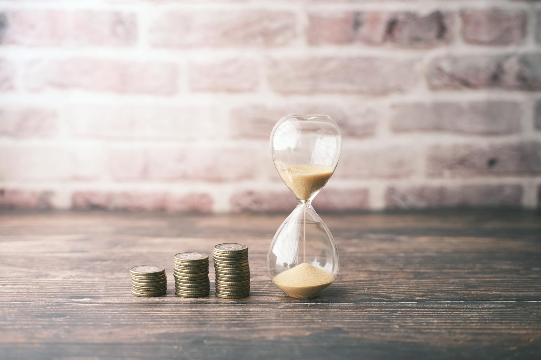 photograph of stacks of coins near an hourglass