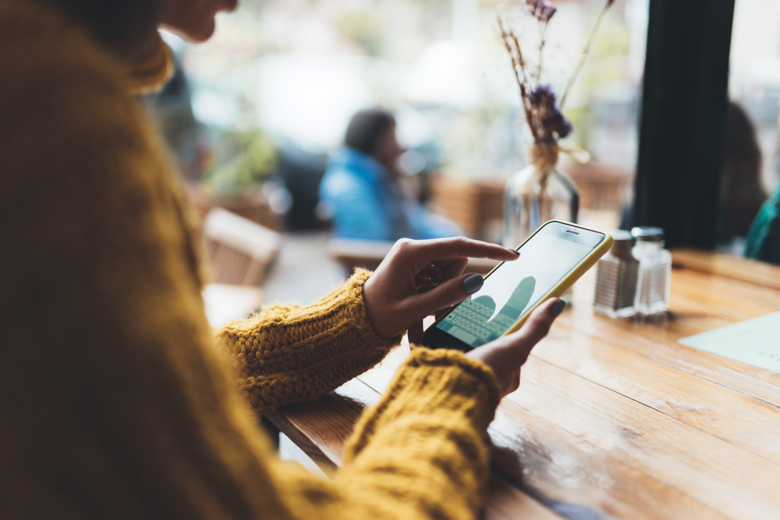 girl hold in hands yellow mobile phone empty screen, person type message on smartphone in sun cafe, relax tourist travels planning trip, hipster enjoy journey in cityscape, lifestyle holiday concept, internet online